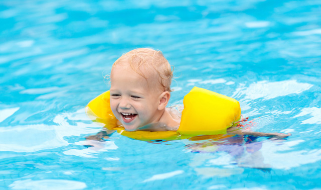 Kleiner Junge mit Schwimmflügel im Wasser